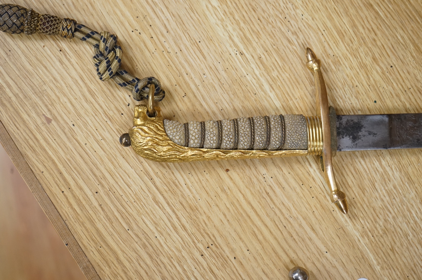 A post 1902 regulation Naval Officer’s dirk with lion’s head pommel, bullion dress knot, shark skin covered grip, in its leather scabbard, the gilt locket engraved with owners initials; CHCO’ R, the blade etched with cro